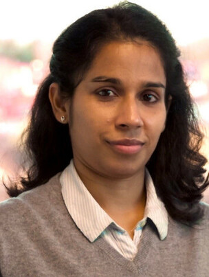 Frau Singha mit dunklem Haar und hellblauer Bluse, ernster Ausdruck.